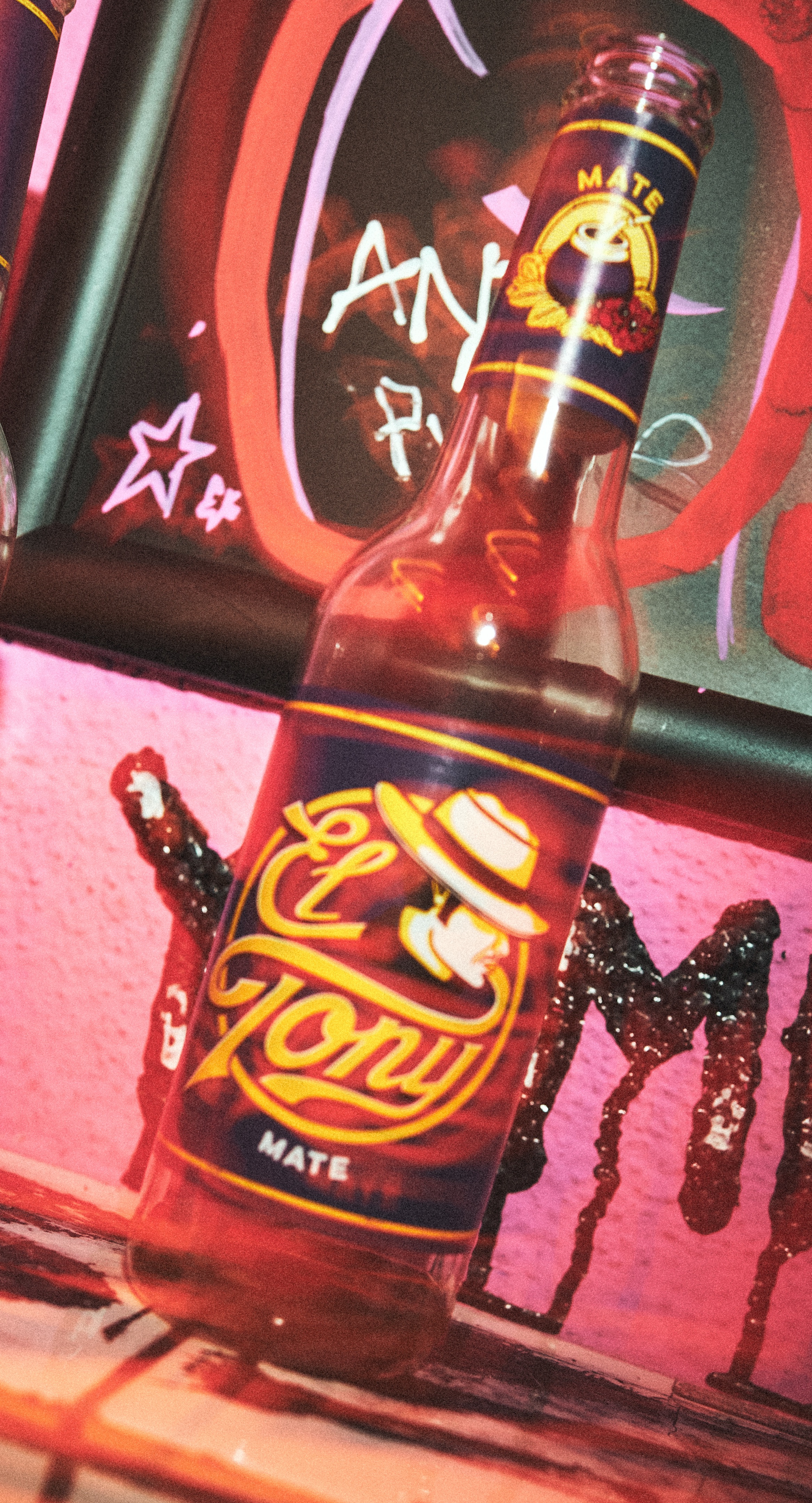 El Tony Mate Getränk in einer Flasche, vor buntem Hintergrund mit Graffiti.