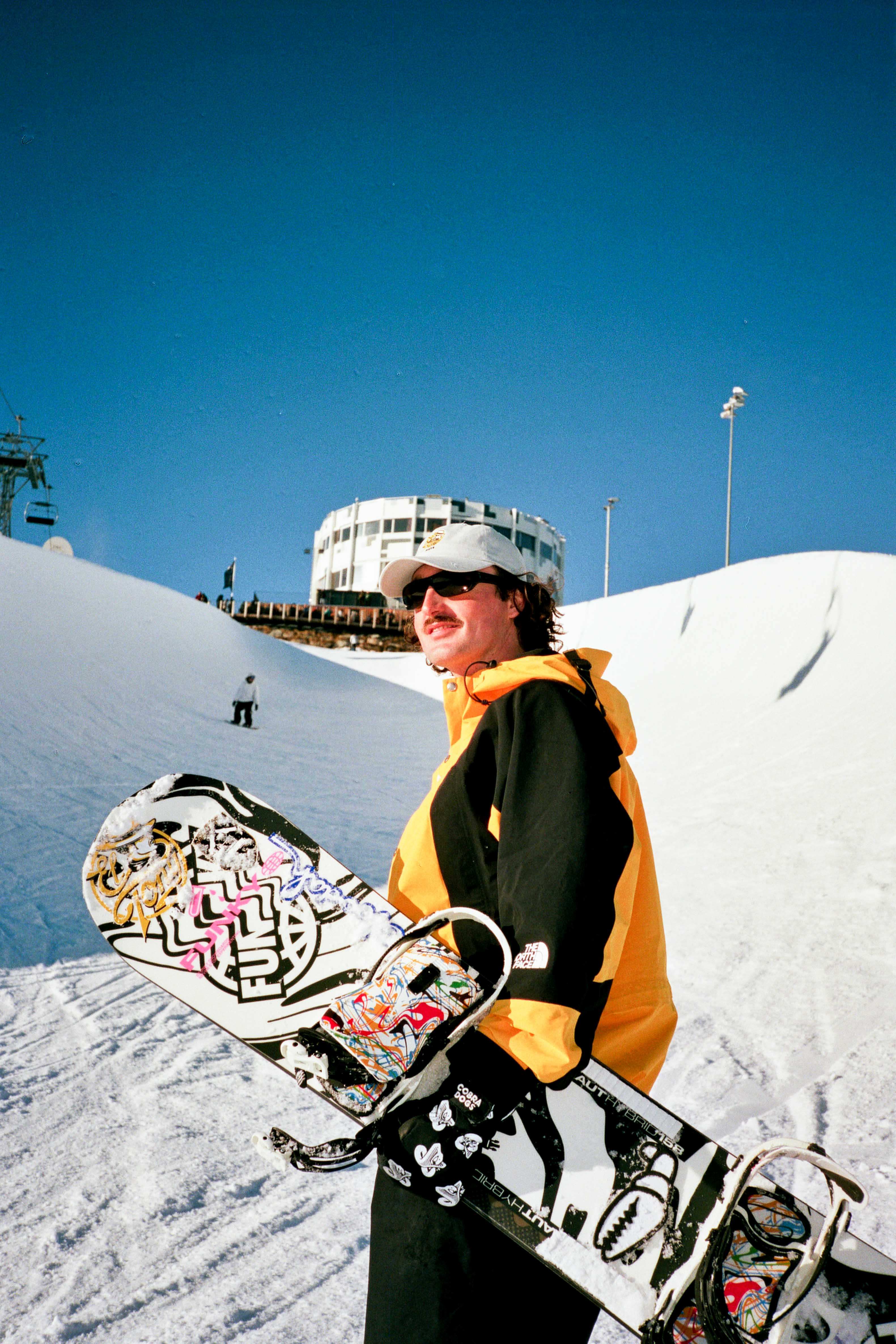 Snowboarder draagt zijn bord in een zonnig sneeuwlandschap, klaar voor de afdaling.