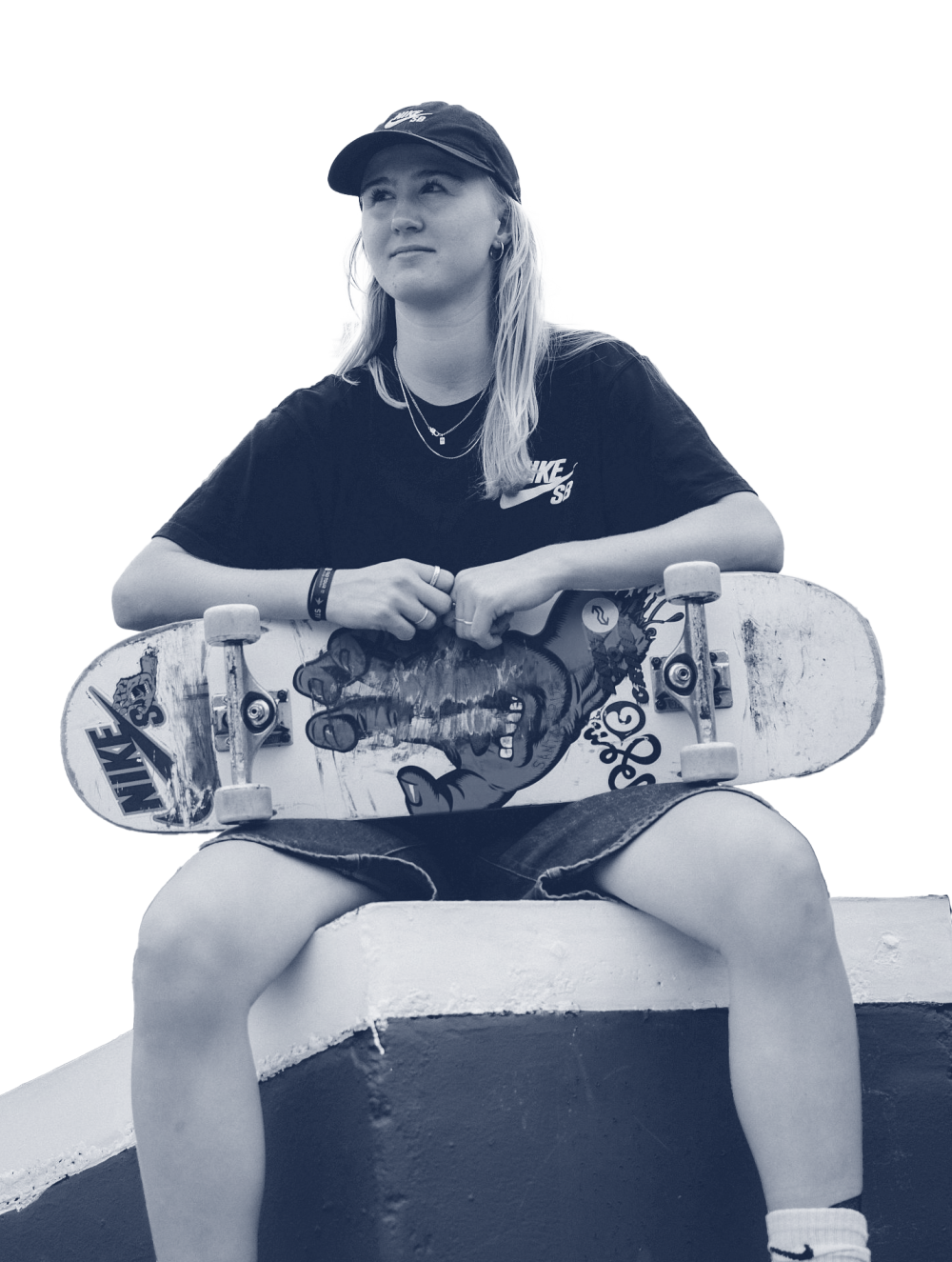Ragazza skater seduta, tiene uno skateboard, indossa un cappellino e guarda lontano.