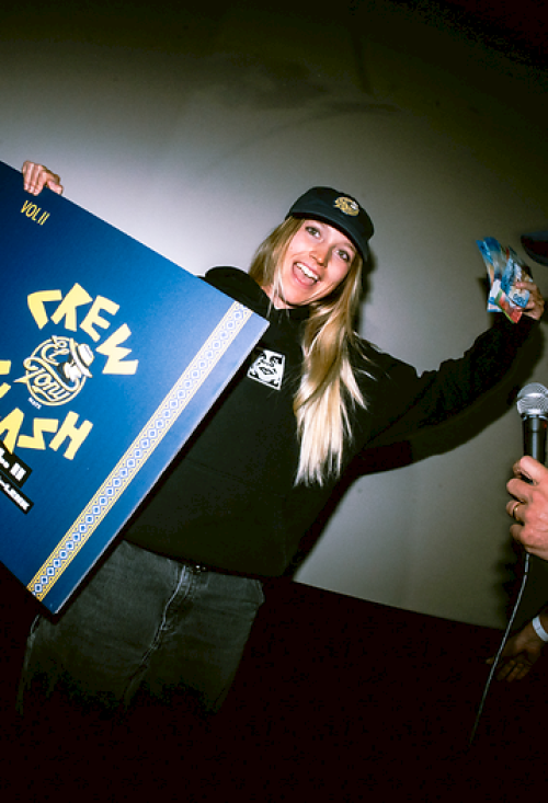 Woman with a prize and beverage, smiling at an event, being interviewed by a man.