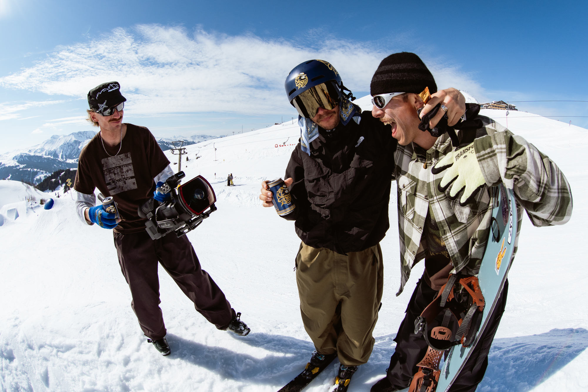 Drei Snowboarder genie&szlig;en einen El Tony Mate auf der Piste bei sonnigem Wetter.