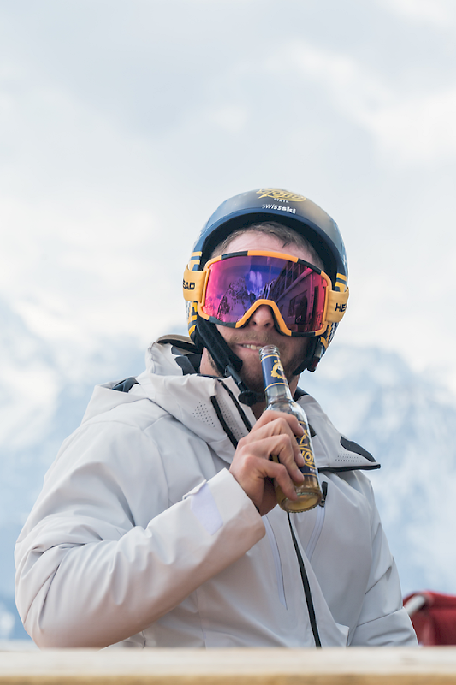 Man met helm en zonnebril houdt een El Tony Mate-fles vast in de bergen.
