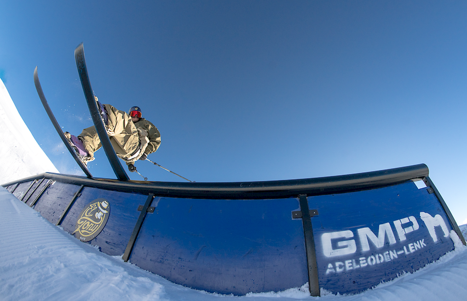 Skifahrer springt über ein Rail im Schnee, El Tony Mate Logo sichtbar.