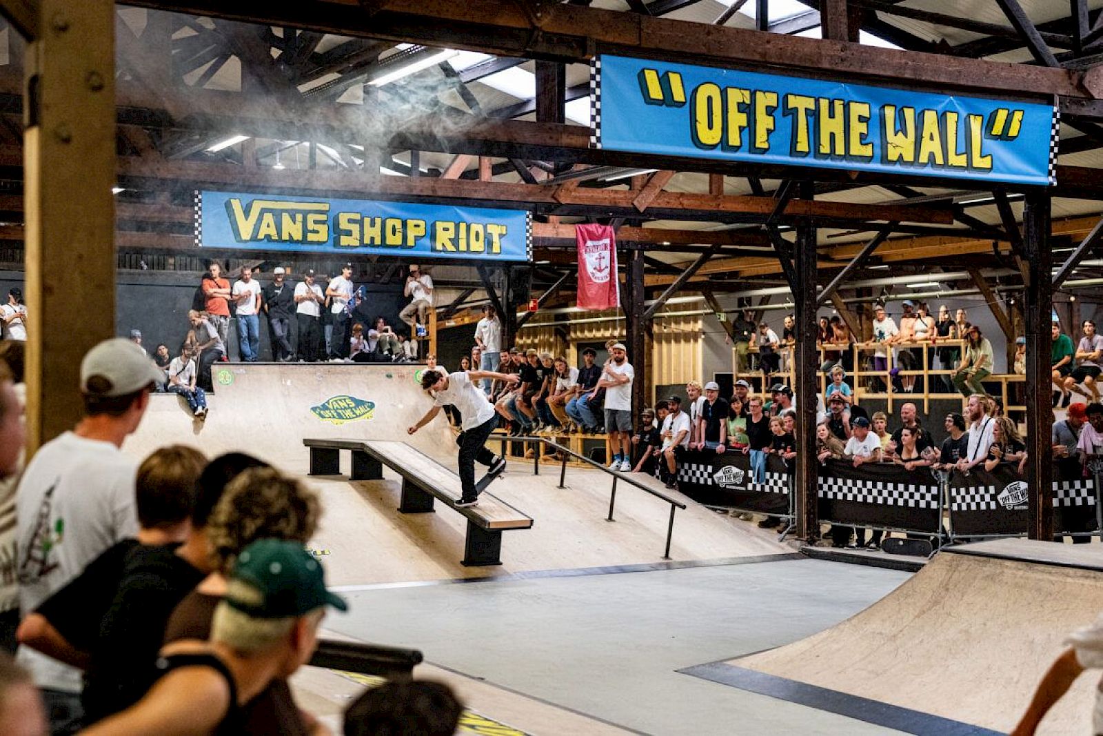 Skateboarder in einer Halle beim Vans Shop Riot, Menschenmenge beobachtet das Event.