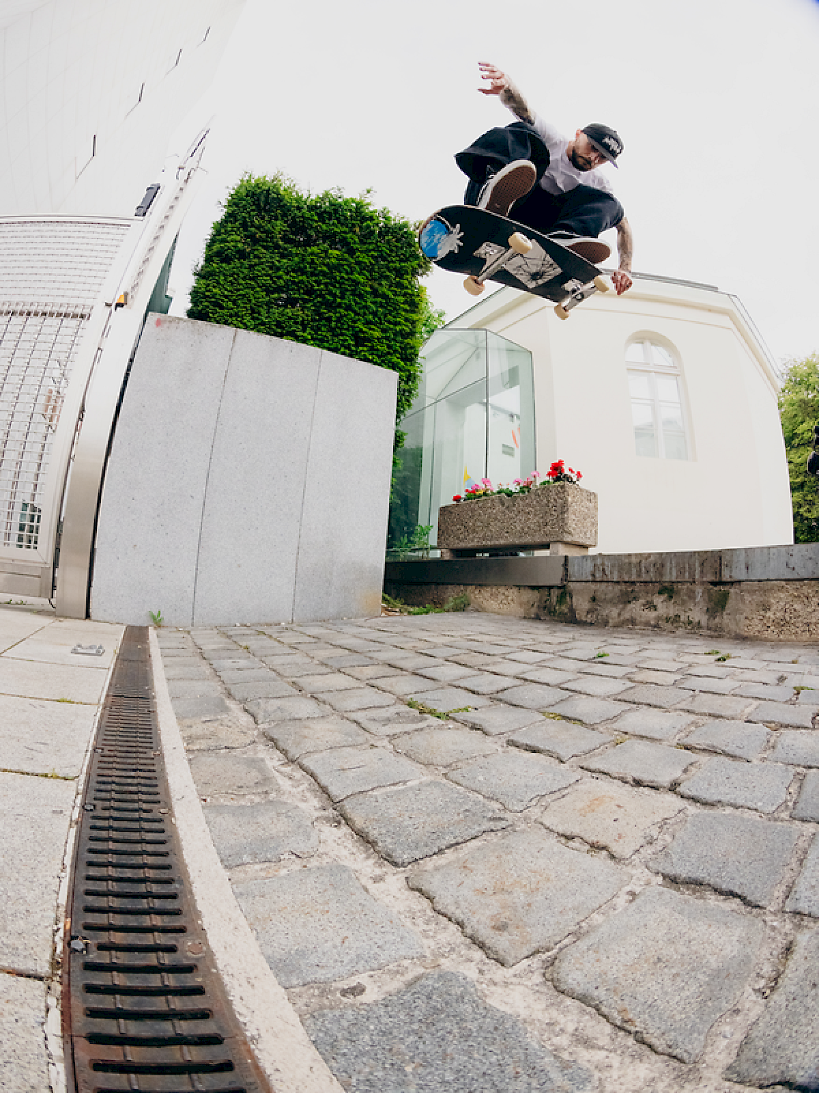 Skater performs a jump over a planter in an urban setting.