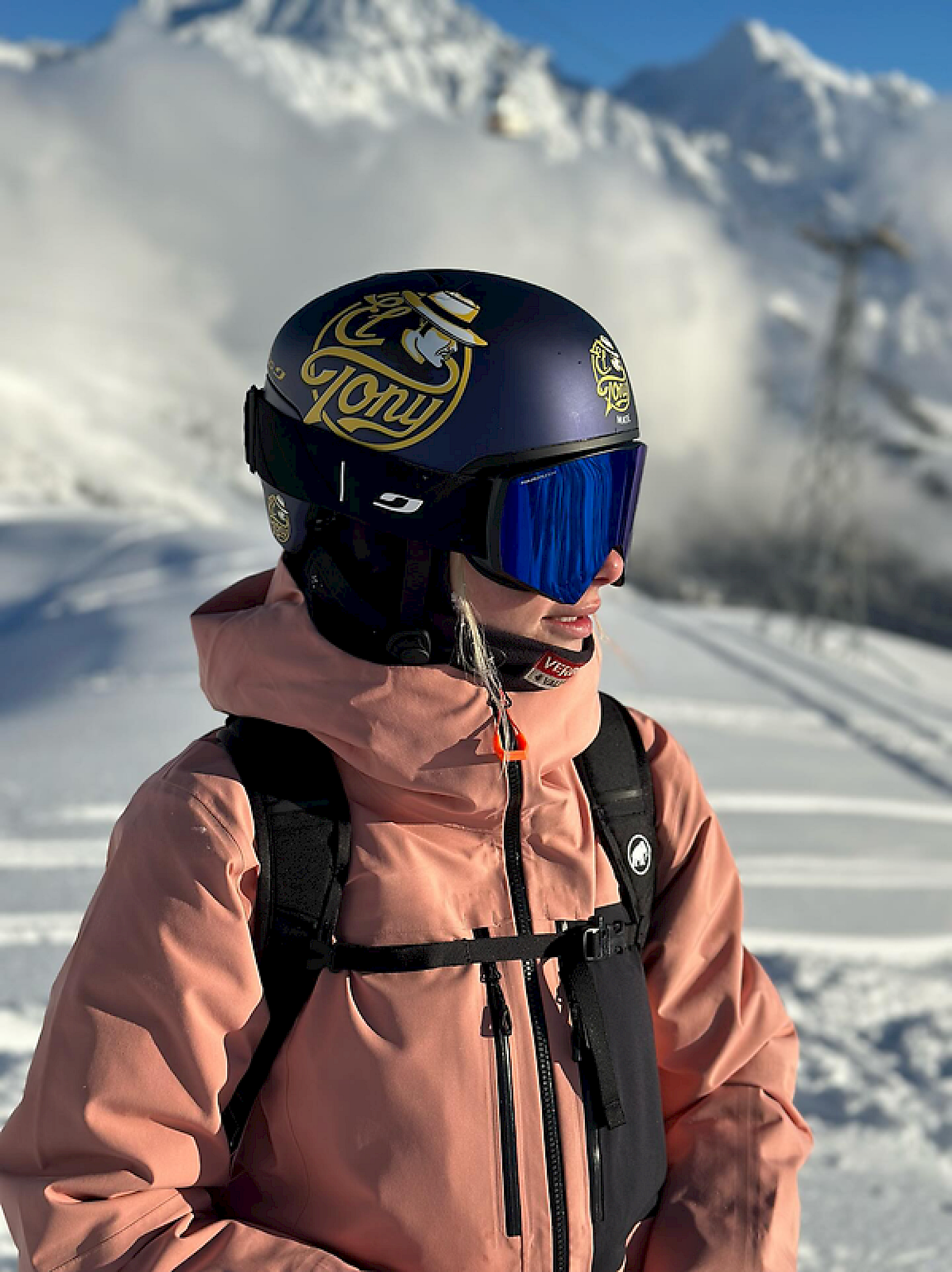 Eine Skifahrerin mit einem El Tony Mate Helm in den Bergen.