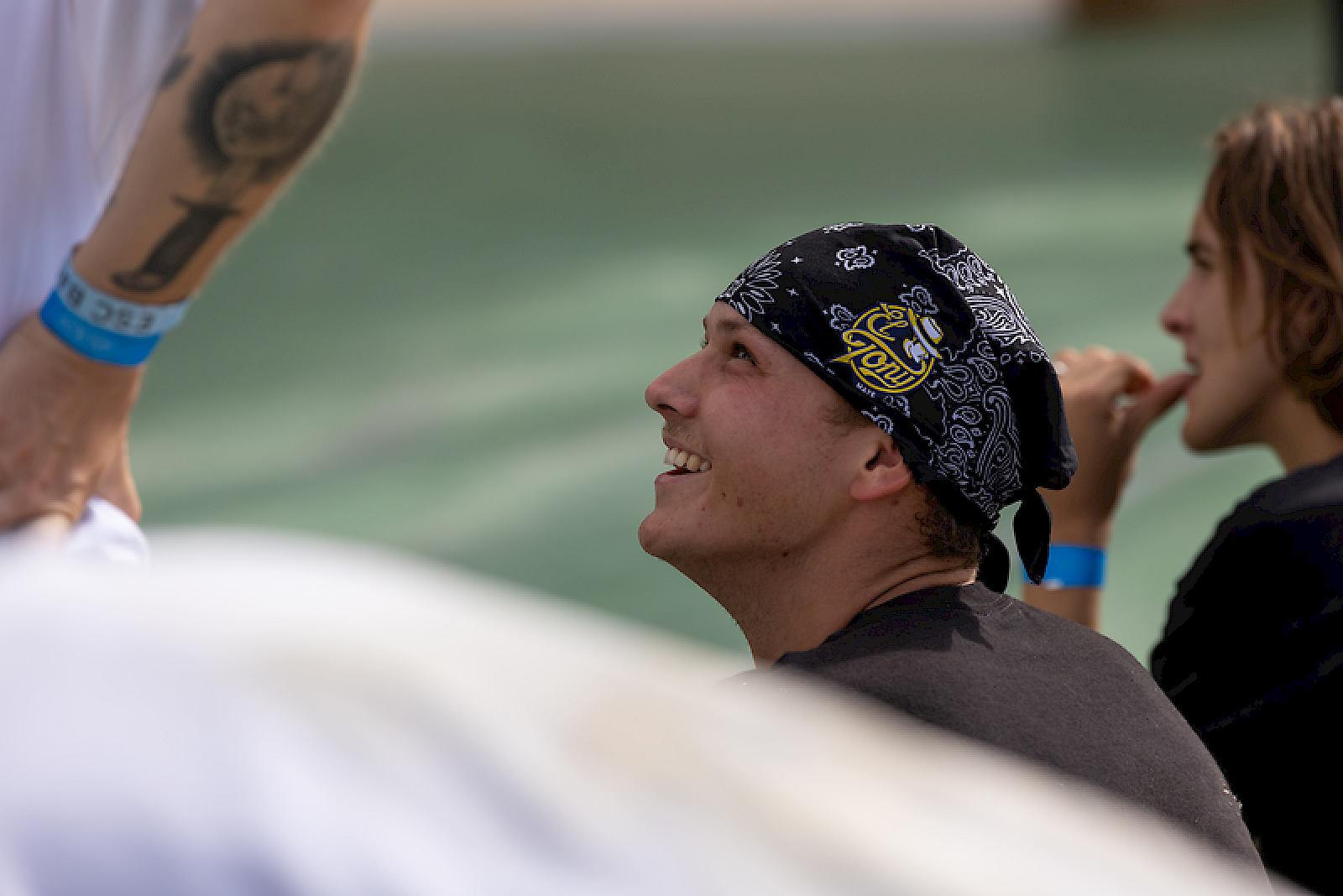 Un giovane con bandana sorride in un'atmosfera rilassata circondato da amici.