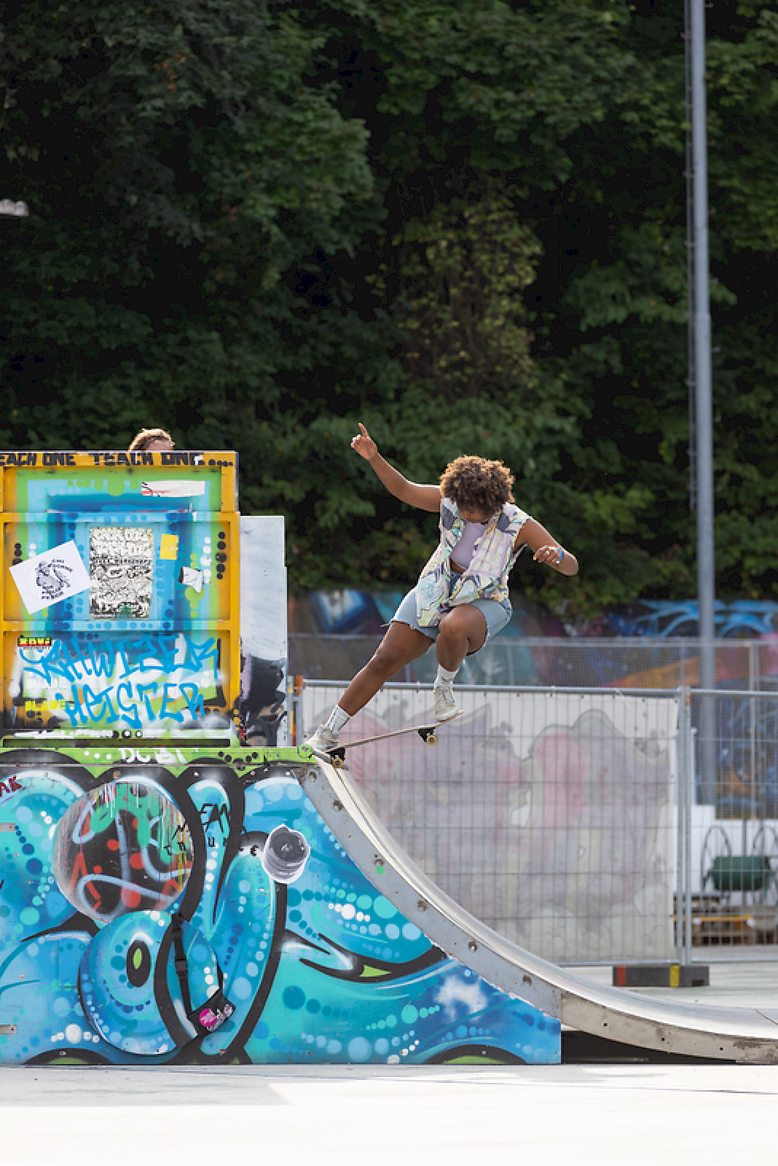 Un skateur effectue un trick sur une rampe avec des graffitis colorés en arrière-plan.