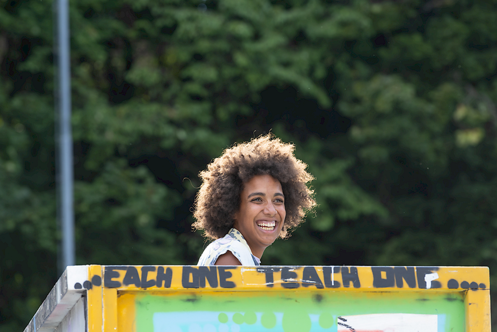 Une femme souriante aux cheveux bouclés dans un cadre coloré promouvant la boisson El Tony Mate.
