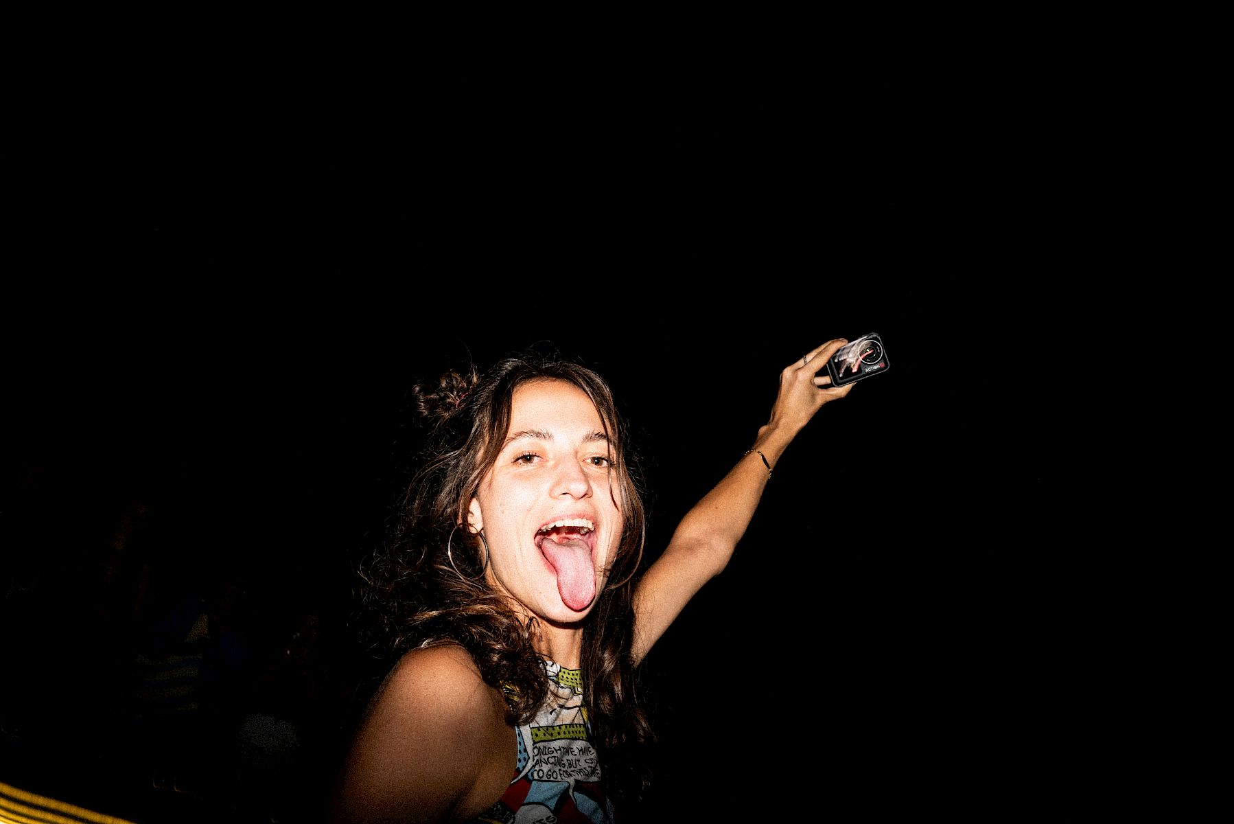 Young woman sticking out her tongue, holding El Tony Mate at a celebration.