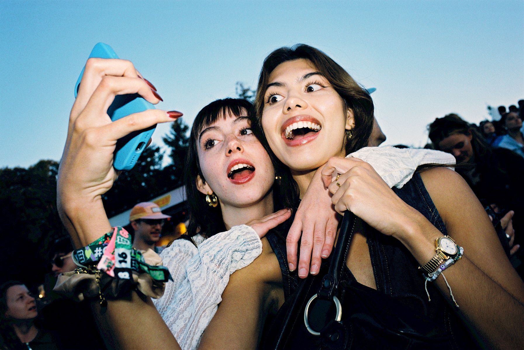 Two women take a selfie, laughing and enjoying a moment at an event with friendly company.