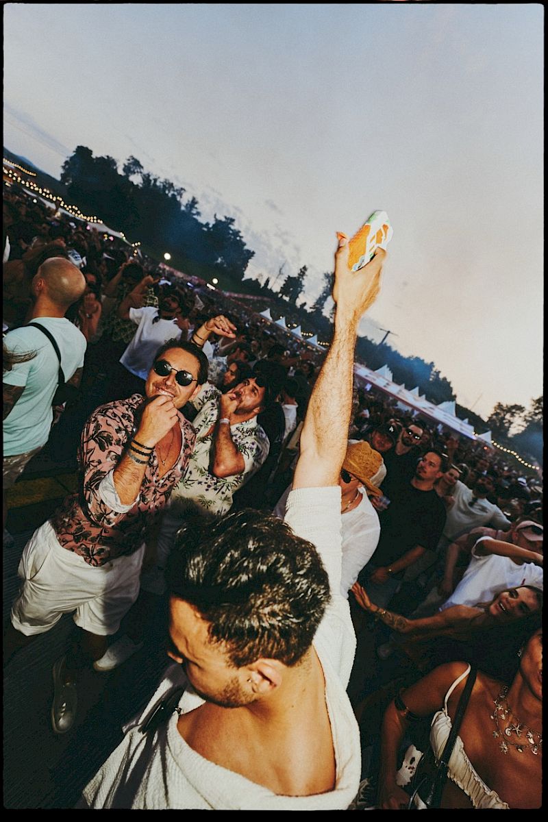 Festivalgoers raise El Tony Mate drinks in a lively crowd.
