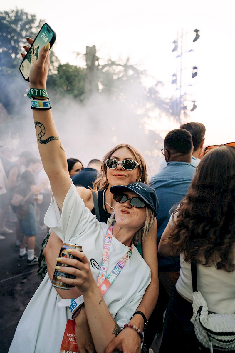Two women enjoy a festival, holding El Tony Mate and having fun amidst the crowd.