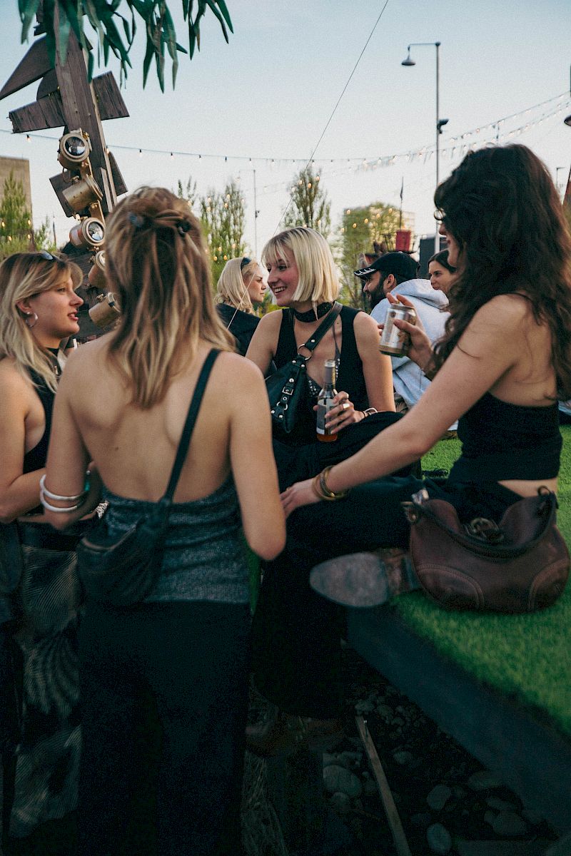 Quattro donne in abbigliamento casual gustano El Tony Mate a un evento all'aperto rilassato.