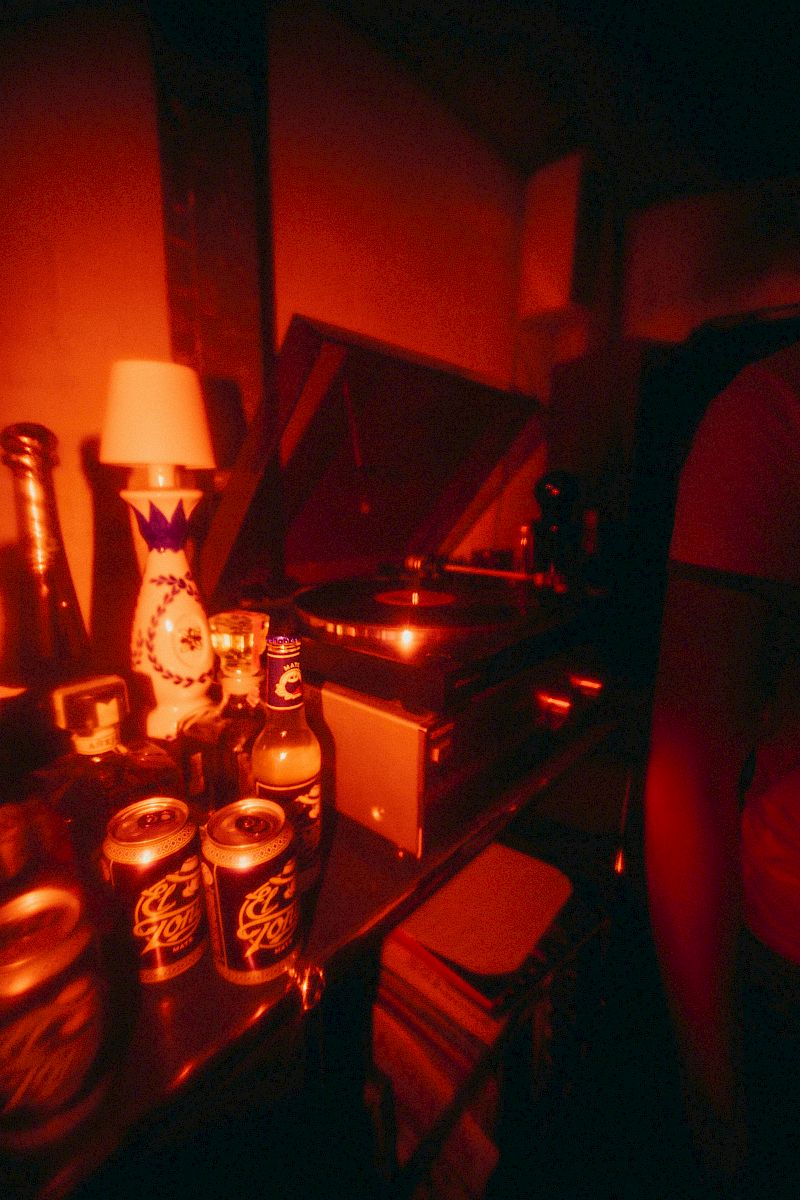 Un giradischi con bevande in una stanza poco illuminata, con un'atmosfera rossa e calda.