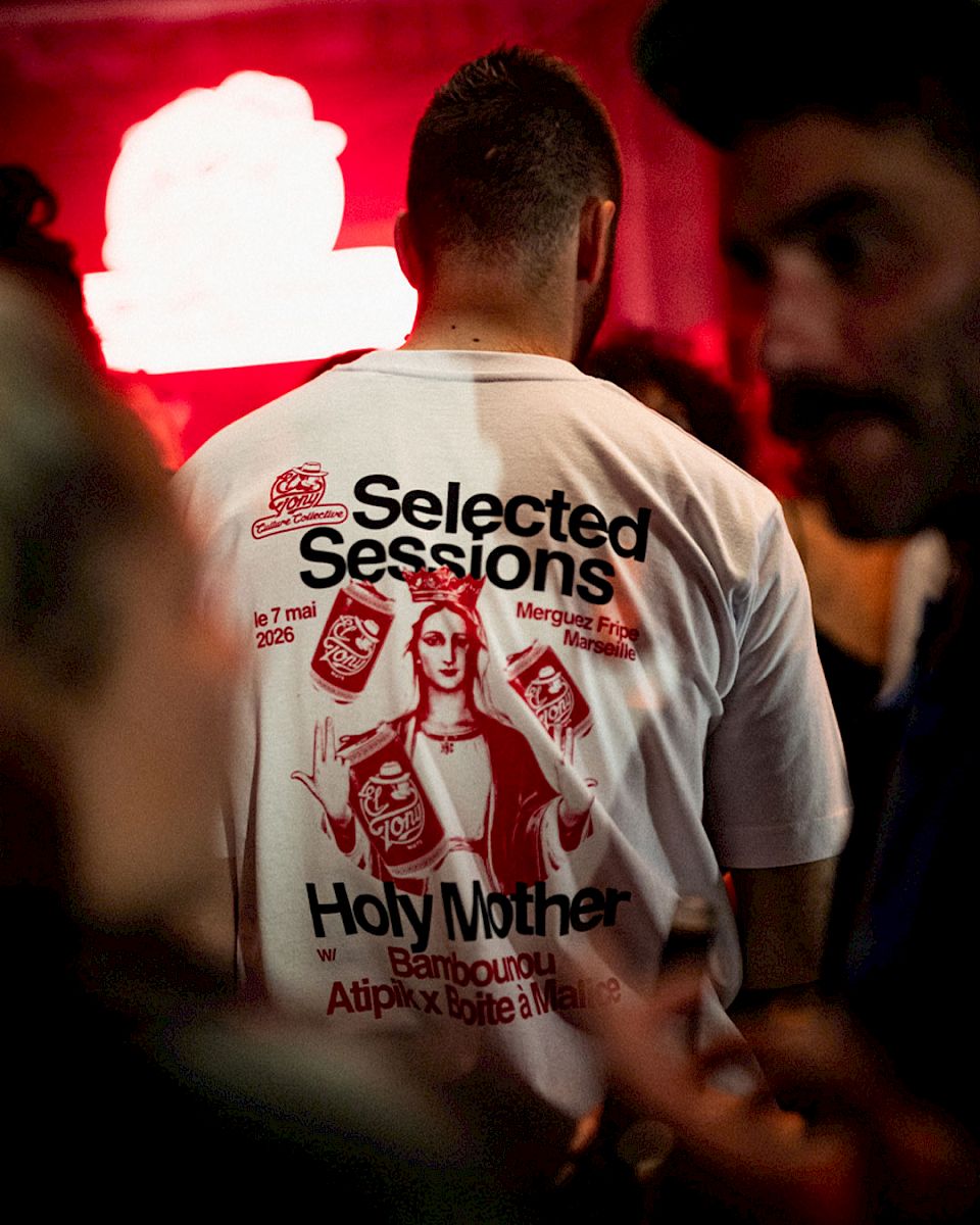 Man in T-shirt met evenementdetails en kunstgrafiek, levendige sfeer op de achtergrond.