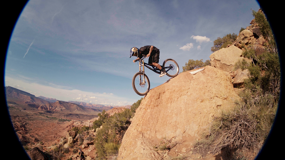 Ciclista di montagna salta da una roccia, godendosi il panorama in un paesaggio desertico.