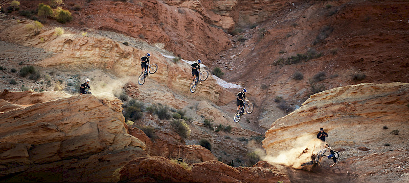 Un ciclista esegue acrobazie in volo sopra le rocce in un paesaggio spettacolare.