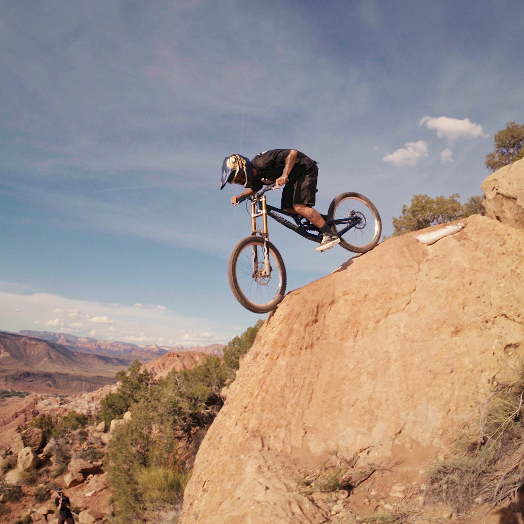 Un mountain biker salta da una roccia in un paesaggio pittoresco.