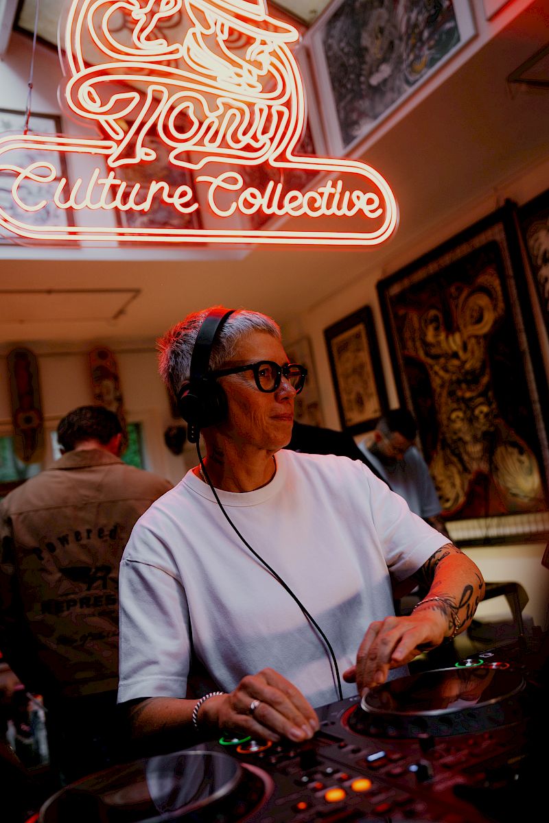 Une DJ femme avec des écouteurs joue dans une pièce avec un éclairage néon.