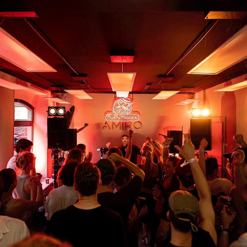 Publiek danst op muziek in een verlichte ruimte met El Tony Mate-dranken.