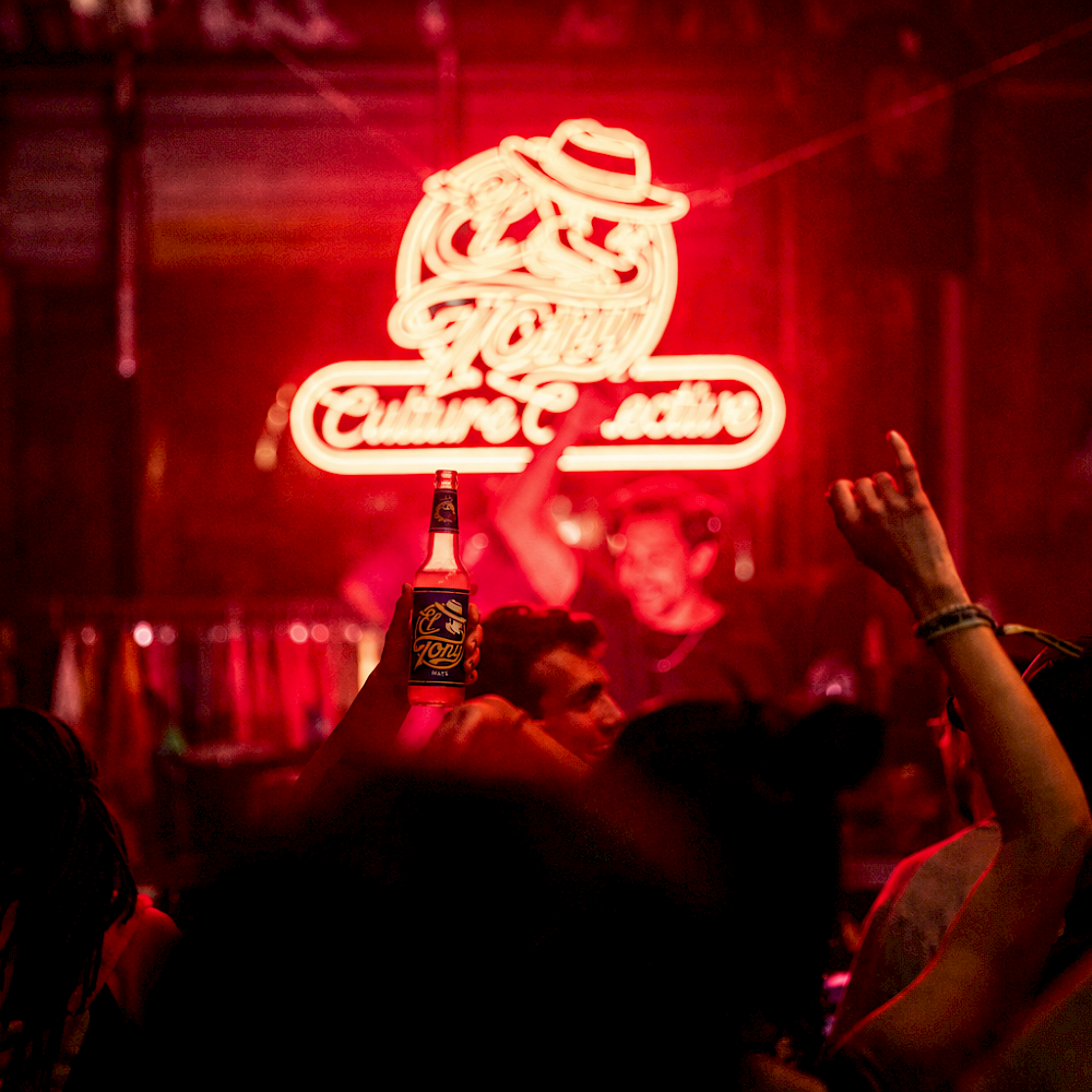 Vibrant night scene with El Tony Mate beverage and a red neon sign.