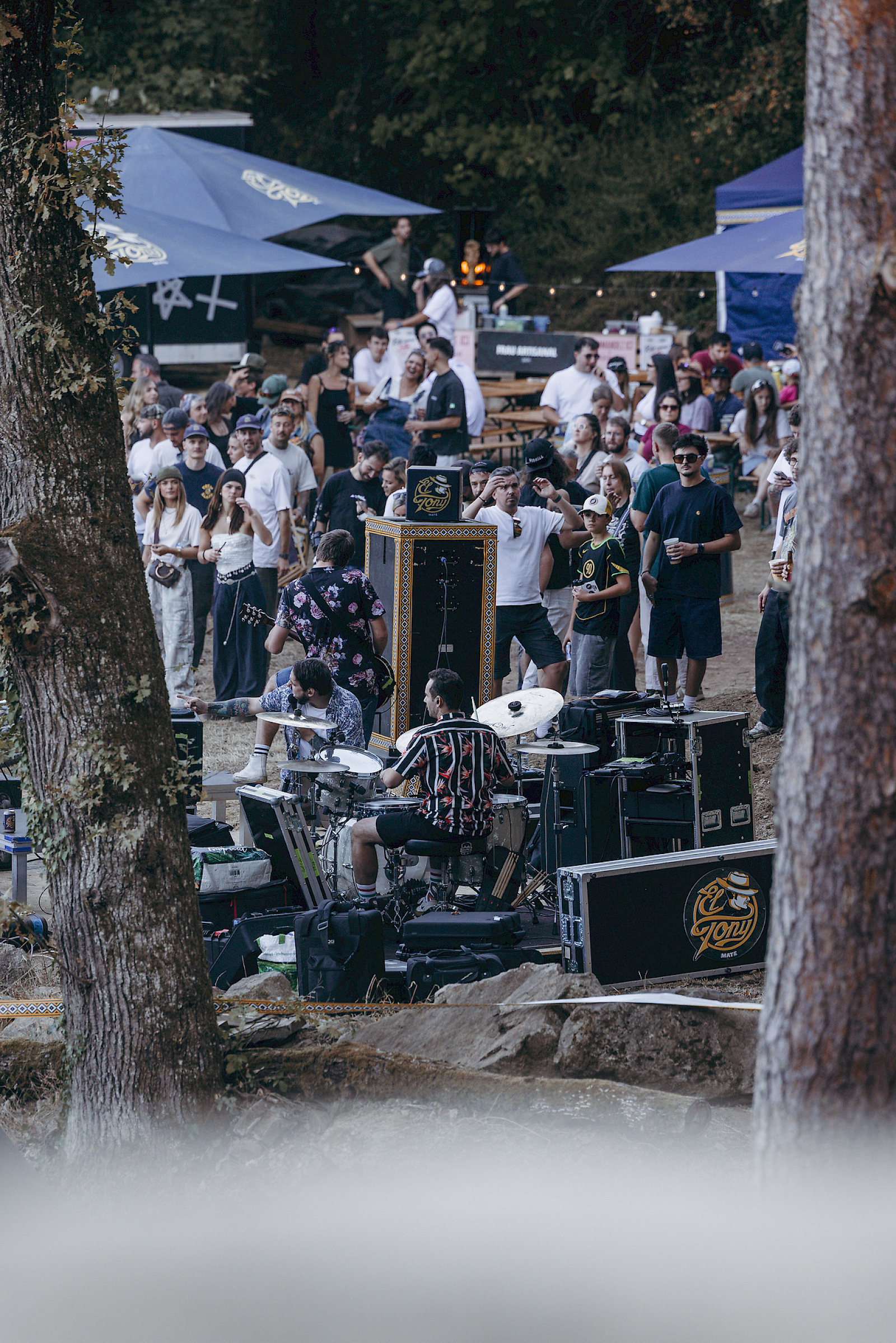 Foule profitant d'un événement musical avec El Tony Mate, boissons et ambiance détendue en plein air.