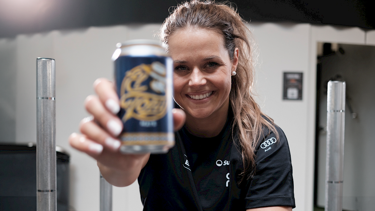 Corinne Suter, im Fitnessstudio hält eine Dose El Tony Mate in der Hand und lächelt.